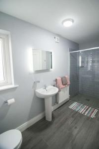 a white bathroom with a sink and a shower at West Haven House in Doolin
