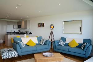 a living room with two blue couches and a table at 29 @ One Lusty Glaze in Newquay