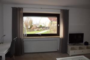 ein Fenster in einem Zimmer mit einem Schreibtisch und einem TV in der Unterkunft FEWO-Horgau in Horgau