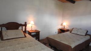 a bedroom with two beds and two lamps on tables at Pircas del Abuelo in Tilcara