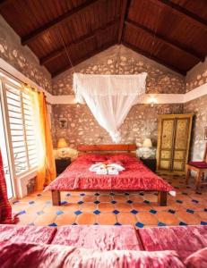 1 dormitorio con 1 cama con colcha roja en Kristal'Inn Cottage Caraibe, en Capesterre