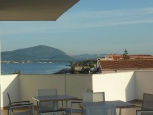 a balcony with tables and chairs and a view of the water at Alma di Alghero Hotel in Alghero