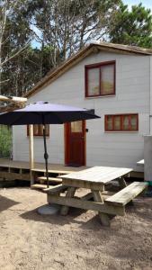 a picnic table with an umbrella in front of a house at Dharma in Punta Del Diablo