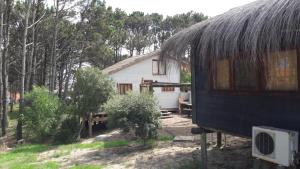 a small house with a thatched roof next to a building at Dharma in Punta Del Diablo