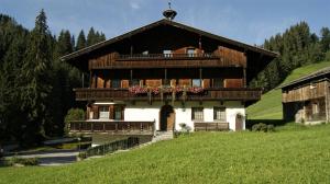 a large wooden house with a balcony in a field at Appartementhaus Talwinkel in Auffach