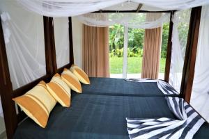 una camera da letto con un letto con cuscini gialli e una finestra di Villa Kaya Guest House a Hikkaduwa