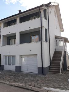 a white house with a gate and a garage at Apartman Anita in Livno