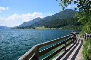 a wooden boardwalk next to a lake with mountains at Haus Schöffau in Strobl