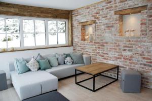 a living room with a couch and a brick wall at Mountainlodge by Skischule Hermann Maier in Flachau