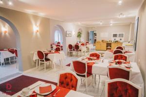 a restaurant with white tables and red chairs at Hotel Carolinensiel Doan in Carolinensiel