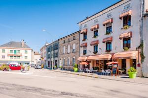 an empty city street with buildings and tables and umbrellas at Le Commerce in Dompaire