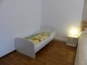 uma cama branca num quarto branco com uma mesa lateral em Ferienwohnung Zur Alten Eiche em Frohburg