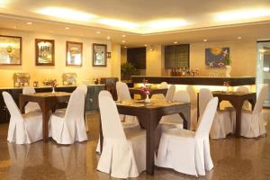 a dining room with two tables and white chairs at Royal Panerai Hotel Chiangmai in Chiang Mai