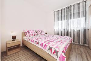 a bedroom with a bed with pink and white sheets and a window at Vila Marijana in Preko