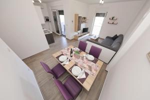 a dining room and living room with a table and purple chairs at Vila Marijana in Preko