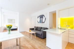 a white kitchen and living room with a couch at Oxford Circus Designer Apartment in London