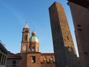 a tall building with a clock on the top of it at Cosmopolitan Central Rooms in Bologna