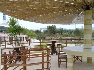 un patio con mesas, sillas y una sombrilla en Anemomili Village, en Kissamos