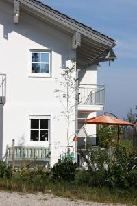 ein weißes Gebäude mit einem Balkon und einem orangenen Regenschirm in der Unterkunft Ferienwohnungen Rimsting am Chiemsee in Rimsting