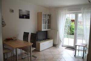 uma sala de estar com uma televisão e uma mesa e cadeiras em Ferienwohnung Charlotte em Ostseebad Karlshagen