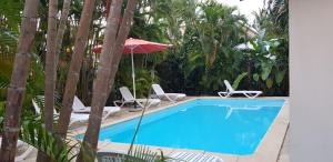 een zwembad met ligstoelen en een parasol bij La Belle Créole in Sainte-Anne