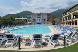 a large swimming pool with lounge chairs next to a building at Giardino dei Colori Appartamenti Dianella Pool relax &family friendly in Toscolano Maderno