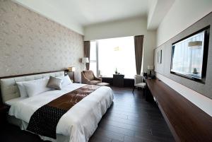 Cette chambre comprend un grand lit et une télévision. dans l'établissement Yuh Tong Hotel, à Chiayi