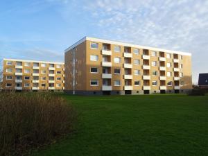 un grand bâtiment avec une pelouse devant lui dans l'établissement Strandperle, à Westerland