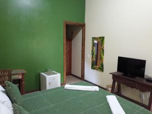 a room with a green wall with a television and a table at Pousada da Terra Paraty in Paraty