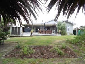 a house with a patio and a yard at Twin Palms in Waikanae