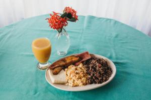 une table avec une assiette de nourriture et un verre de jus d'orange dans l'établissement Hotel Javy, à Liberia