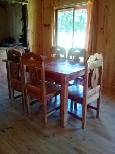 mesa de comedor de madera con sillas, mesa y ventana en Cabañas piedra Alta, Huilo Huilo, en Panguipulli
