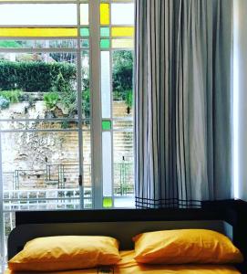 Bett mit zwei Kissen vor dem Fenster in der Unterkunft PrimoPianoPosillipo in Neapel
