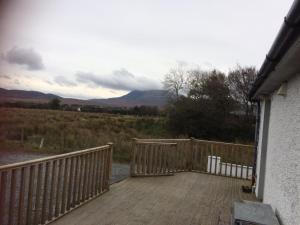 une terrasse en bois avec une clôture et des montagnes en arrière-plan dans l'établissement Teach Barney, à Falcarragh