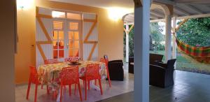 een eetkamer met een tafel en rode stoelen bij La Belle Créole in Sainte-Anne