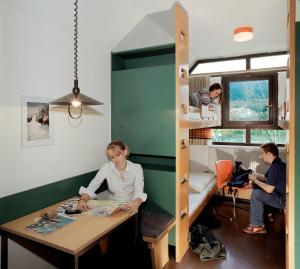 kobieta siedząca przy stole w małym domku w obiekcie Jugendherberge Innsbruck - Youth Hostel w mieście Innsbruck