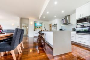 a kitchen with white cabinets and a table and chairs at Leven River Retreat in Ulverstone