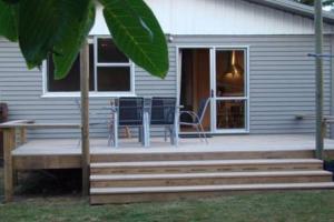 a house with a porch with a table and chairs at Walnut Cottage, Turangi/Tongariro in Turangi