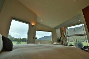 a bedroom with a large bed and large windows at Ironstone Romantic Couples Retreat in Halls Gap