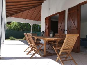 Villa les Lataniers St-Francois في سانت فرانسوا: طاولة وكراسي خشبية على الفناء