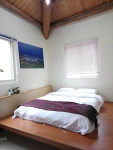 1 cama en un dormitorio con 2 ventanas en Jinsha Sea Cloud B&B, en Nangan