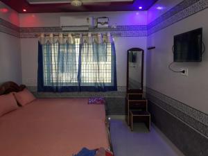 Schlafzimmer mit einem Bett, einem Spiegel und violetten Lichtern in der Unterkunft Sri Priya Lodge in Dharmapuri