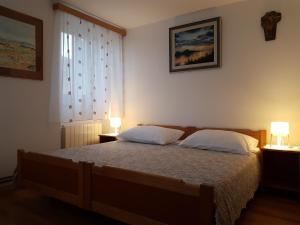 ein Schlafzimmer mit einem Bett mit zwei Kissen und zwei Lampen in der Unterkunft Cres view apartments in Cres