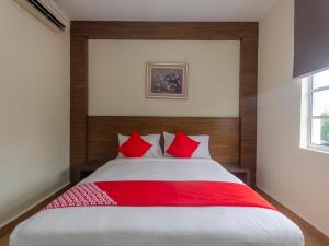 a bedroom with a large bed with red pillows at Super OYO 596 The Vintage Hotel in Nusajaya