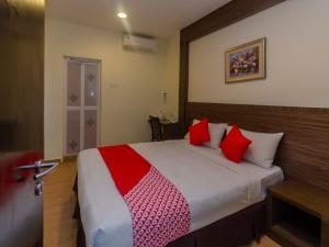 a bedroom with a large bed with red pillows at Super OYO 596 The Vintage Hotel in Nusajaya