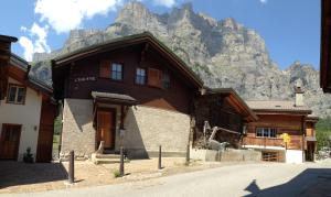 un gran edificio de madera con una montaña en el fondo en L'Eau-Vive, en Leukerbad