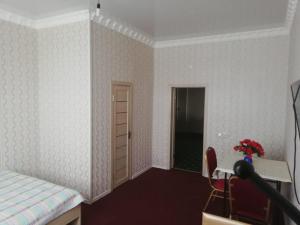 a bedroom with a bed and a table and a door at Керуен сарайы, гостиница in Aralʼsk