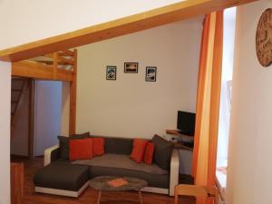 a living room with a gray couch with orange pillows at Vila Lomnička in Vysoke Tatry - Tatranska Lomnica.