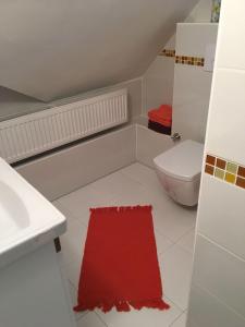a bathroom with a toilet and a red rug at Vila Lomnička in Tatranská Lomnica