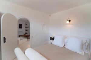 een witte slaapkamer met een bed met witte kussens bij Lithia Villas in Chora Folegandros